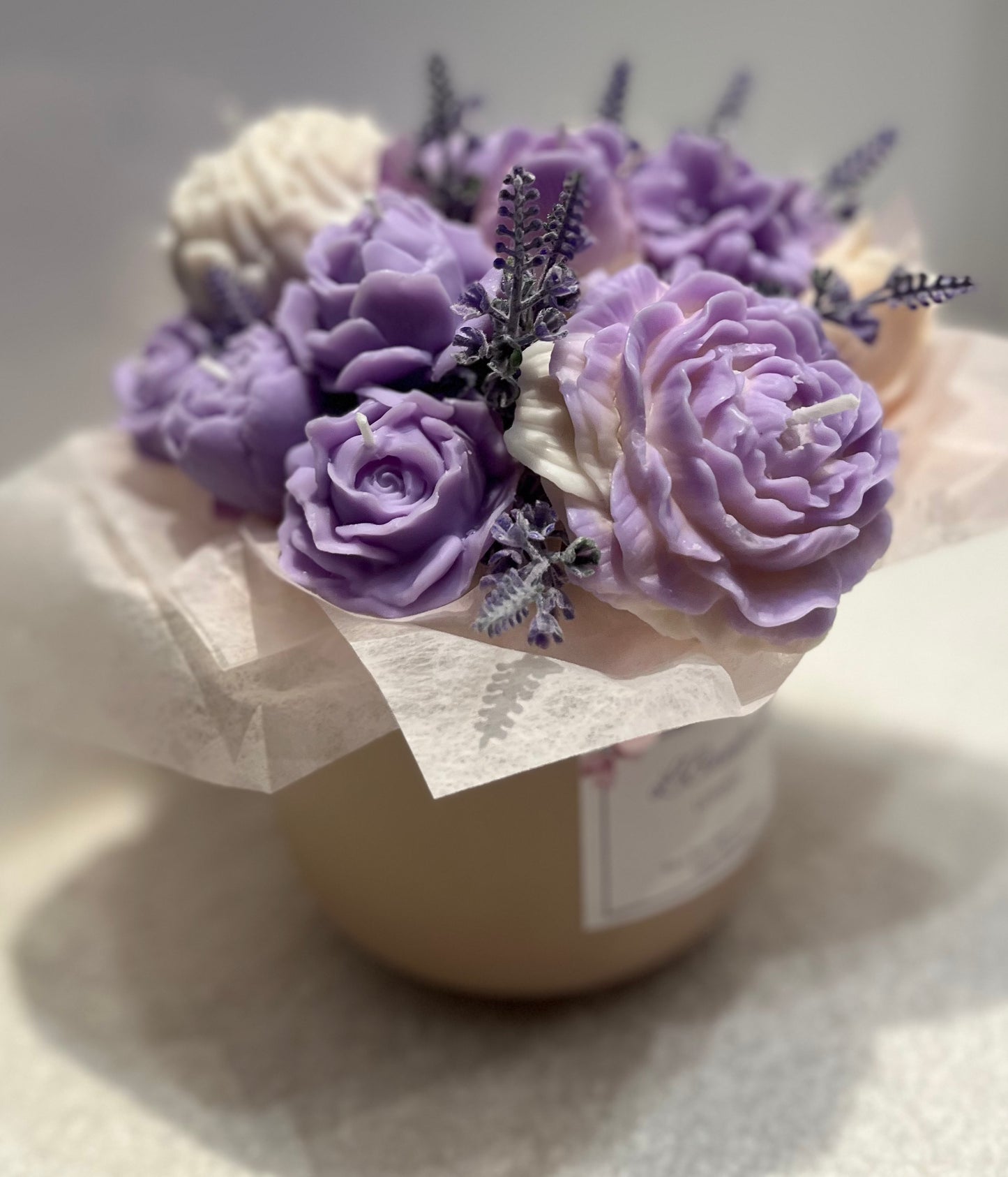 Decorative candle with purple and white flowers on a light background