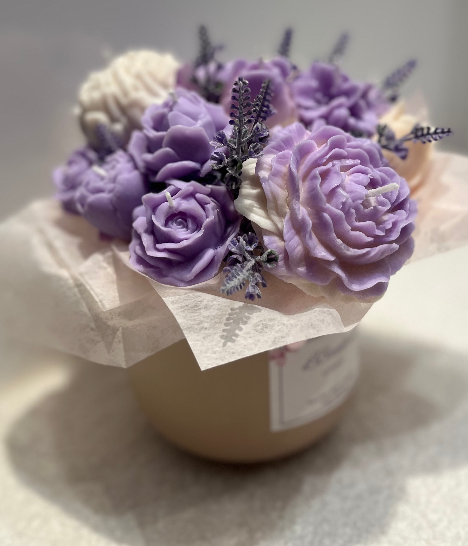 Decorative candle with purple and white flowers on a light background