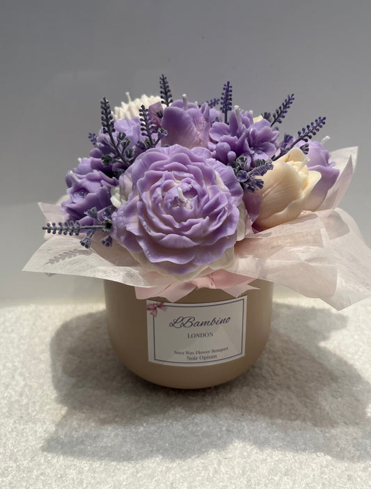 Decorative arrangement of purple and white flowers in a beige pot on a light gray background