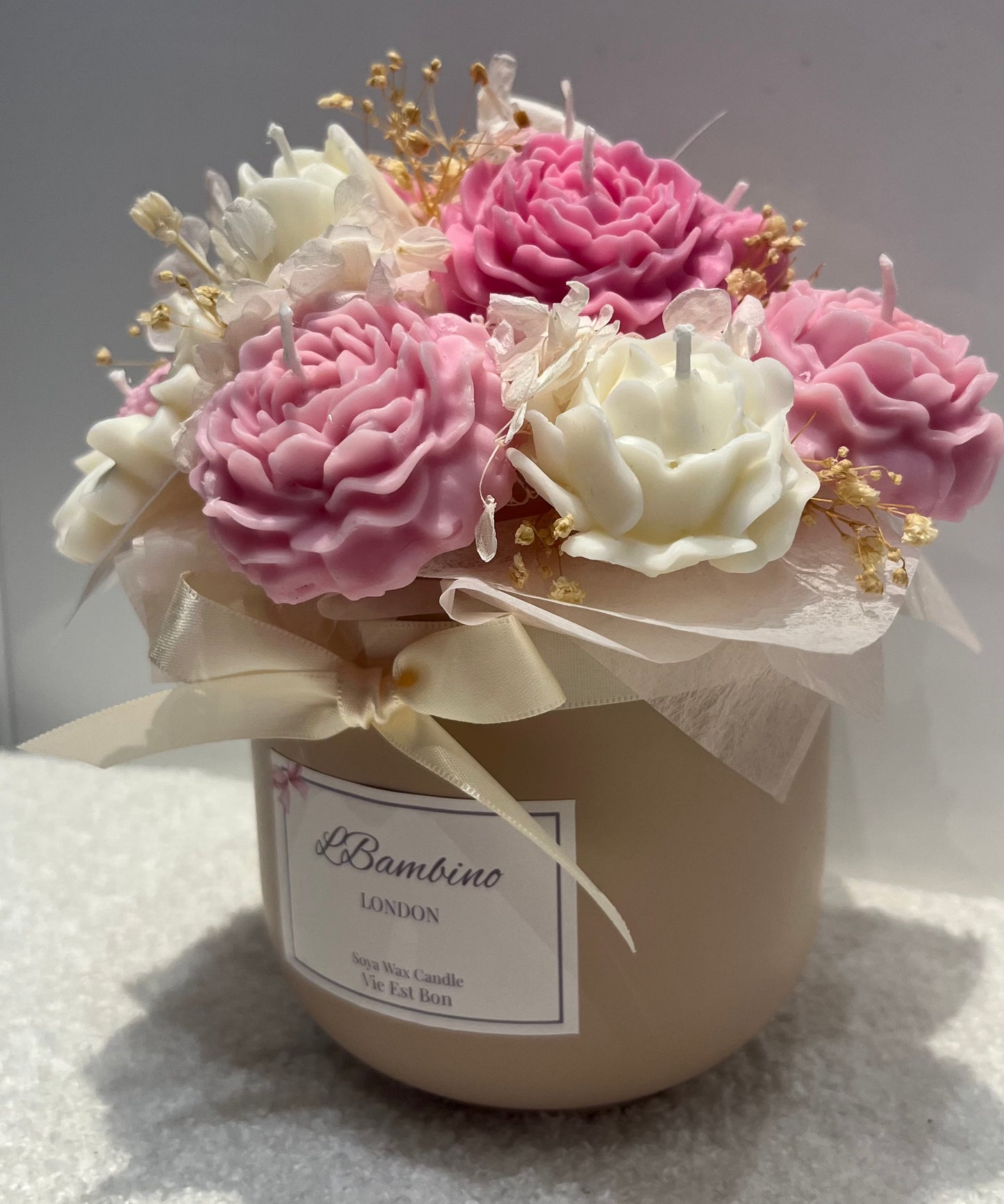 Decorative candle with pink and white flowers in a container labeled 'L.Bambino London'.