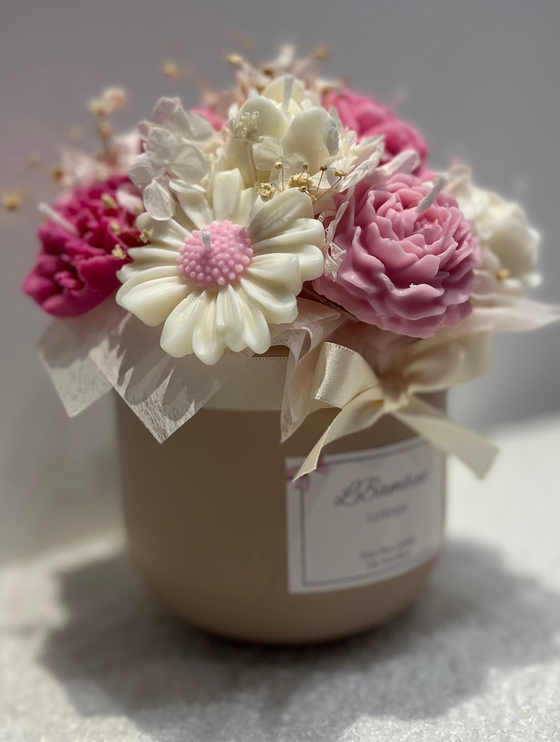 Decorative flower arrangement in a small jar with a label on a light background