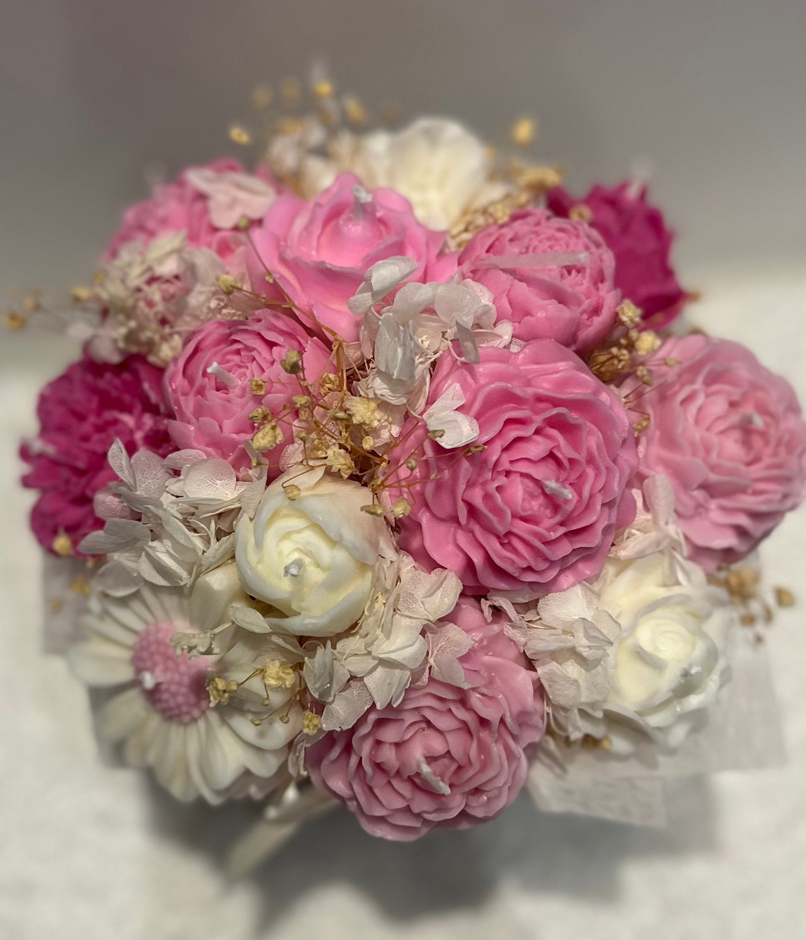 Bouquet of pink and white flowers with gold accents on a light background