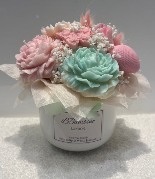 Decorative candle with pink and green flowers and a visible brand label on a light background