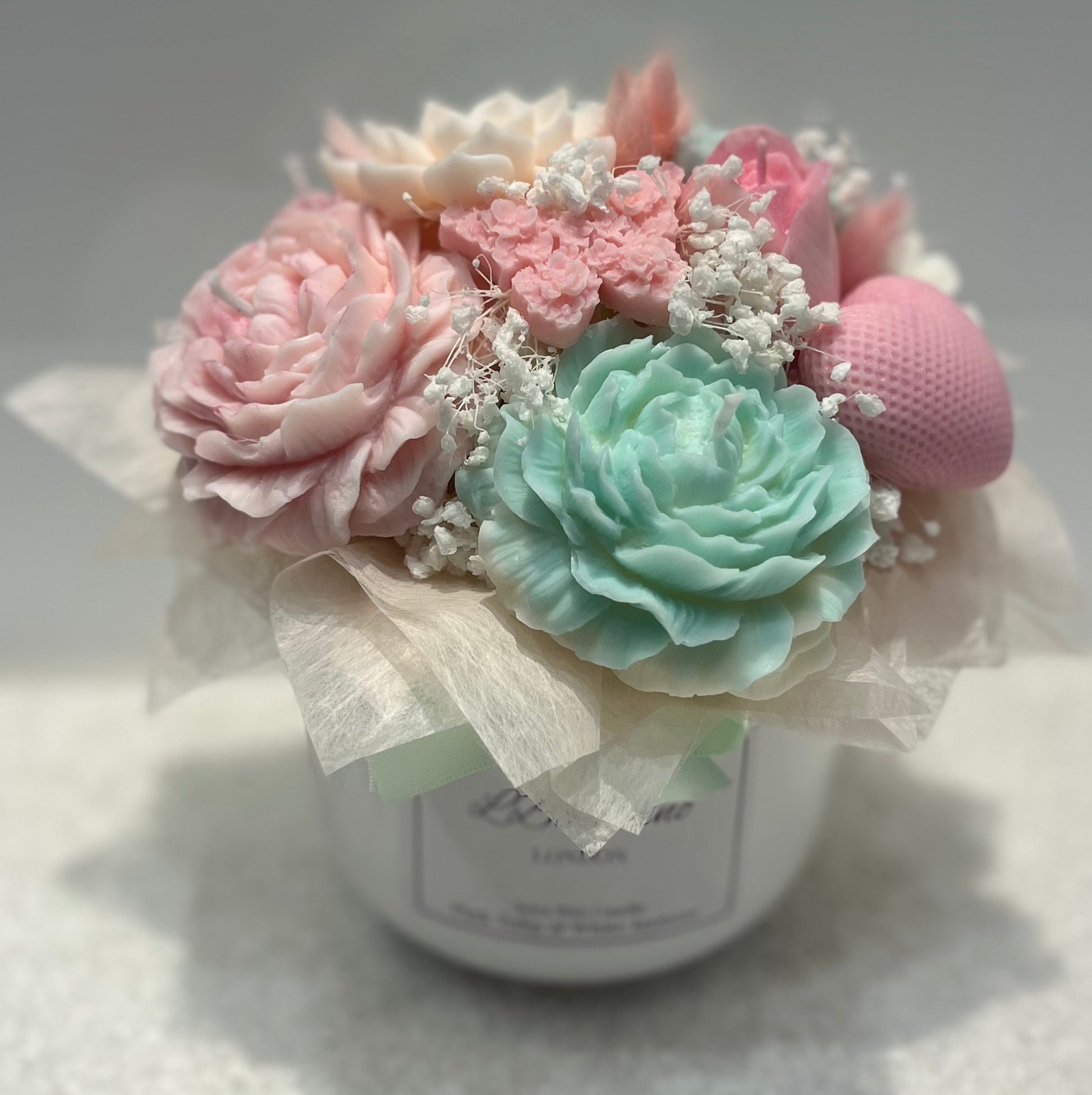 Decorative flower arrangement in a white container with pink and green flowers on a light background