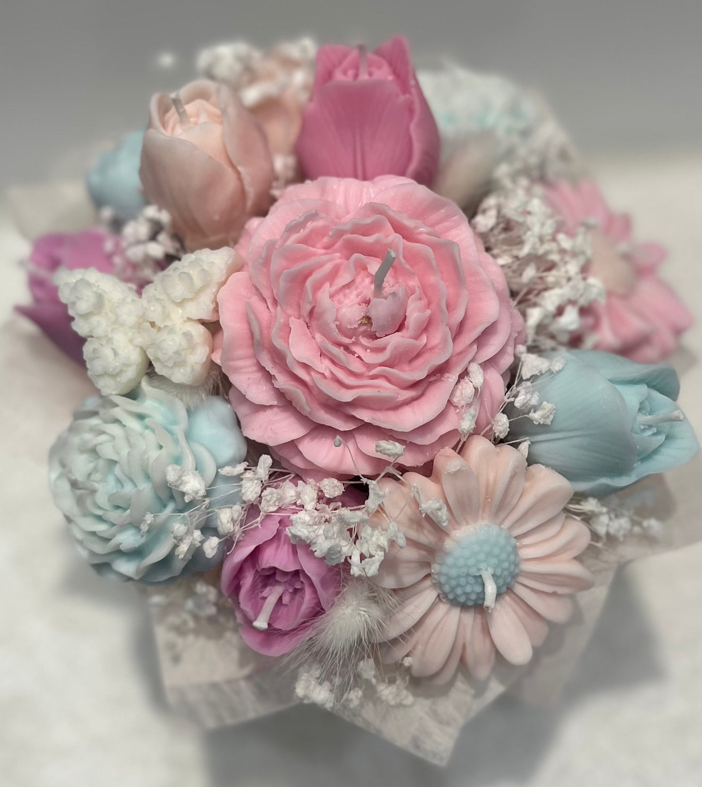 Pastel-colored flower arrangement with pink, blue, and white flowers on a light background