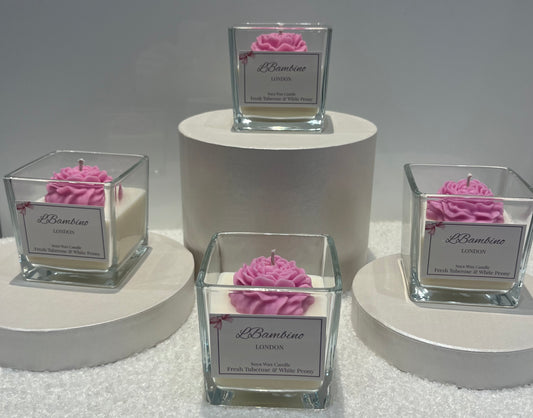 Four square glass candle holders with pink rose candles on white stands against a gray background