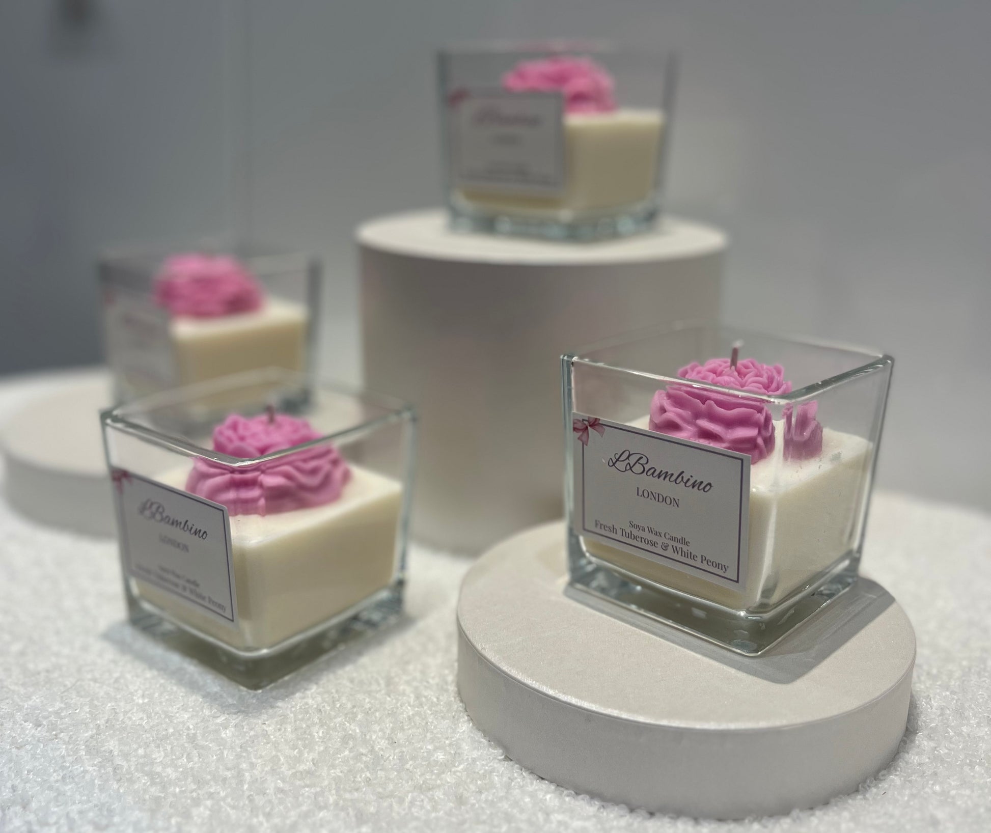 Small square glass containers with pink floral decorations on a white surface.